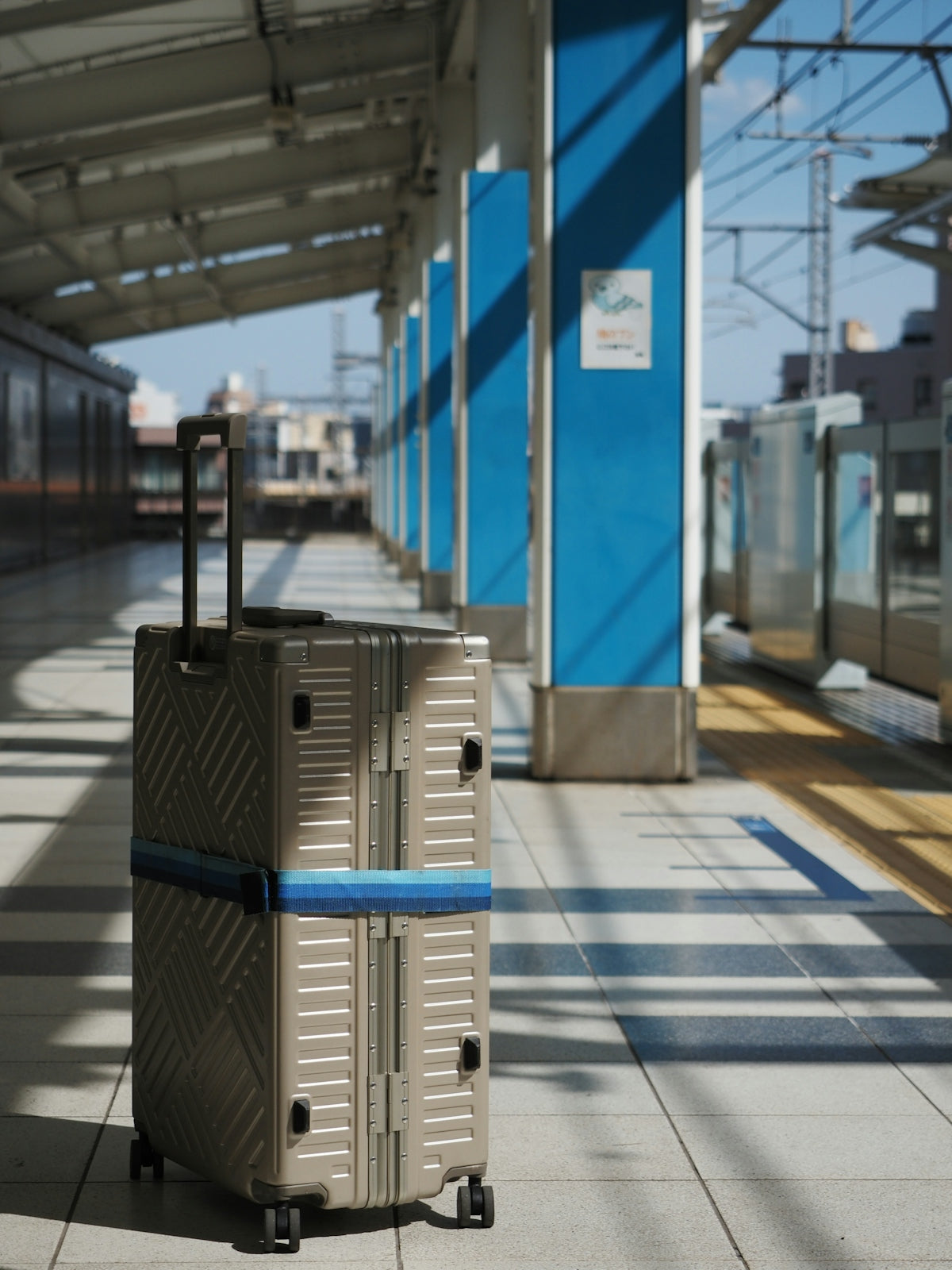 Two stacked suitcases on a train platform.